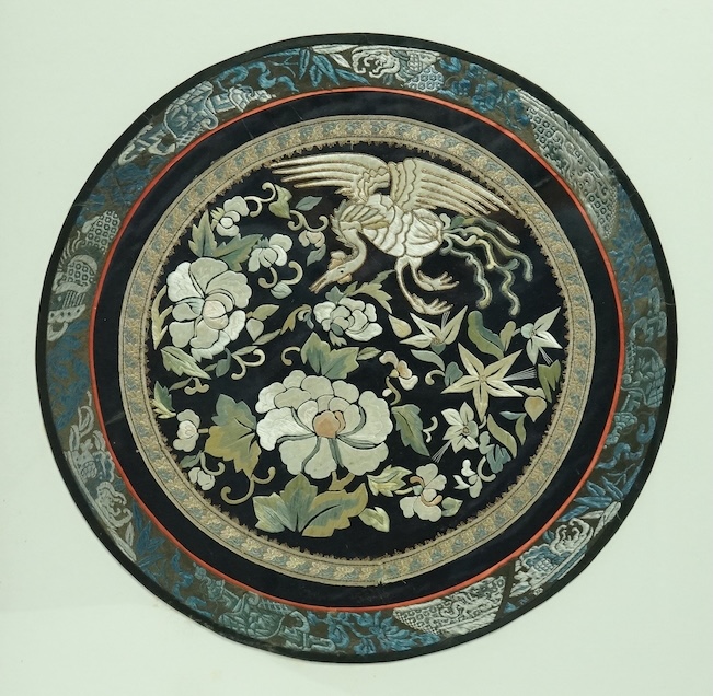 A large framed Chinese early 20th century embroidered roundel. Embroidered with a central motif of a phoenix and flowers, surrounded by gold braiding and a blue embroidered edging. 37cm diameter. Condition - good colours